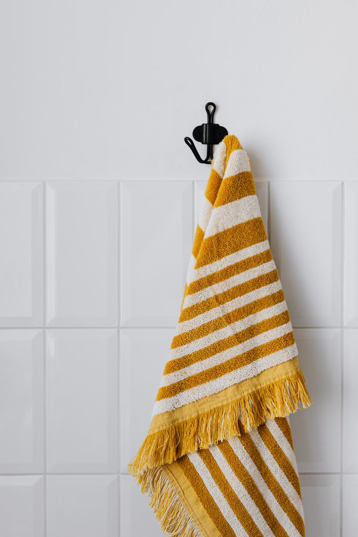 mobile-01 A stylish striped yellow and white towel hanging on a wall hook in a bathroom setting.
