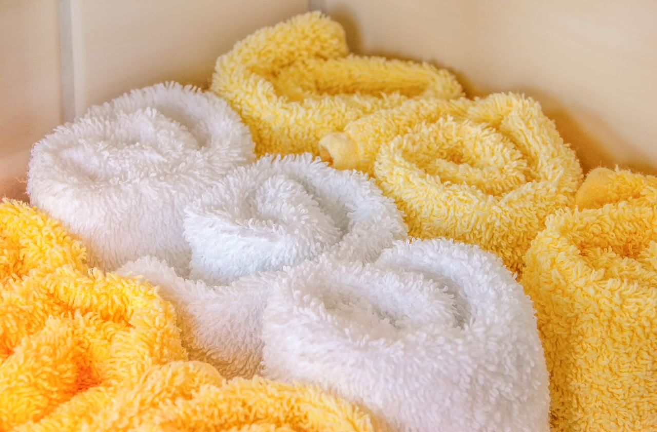 creative-01 Neatly arranged rolled white and yellow towels in a bathroom setting for hygiene and decor.